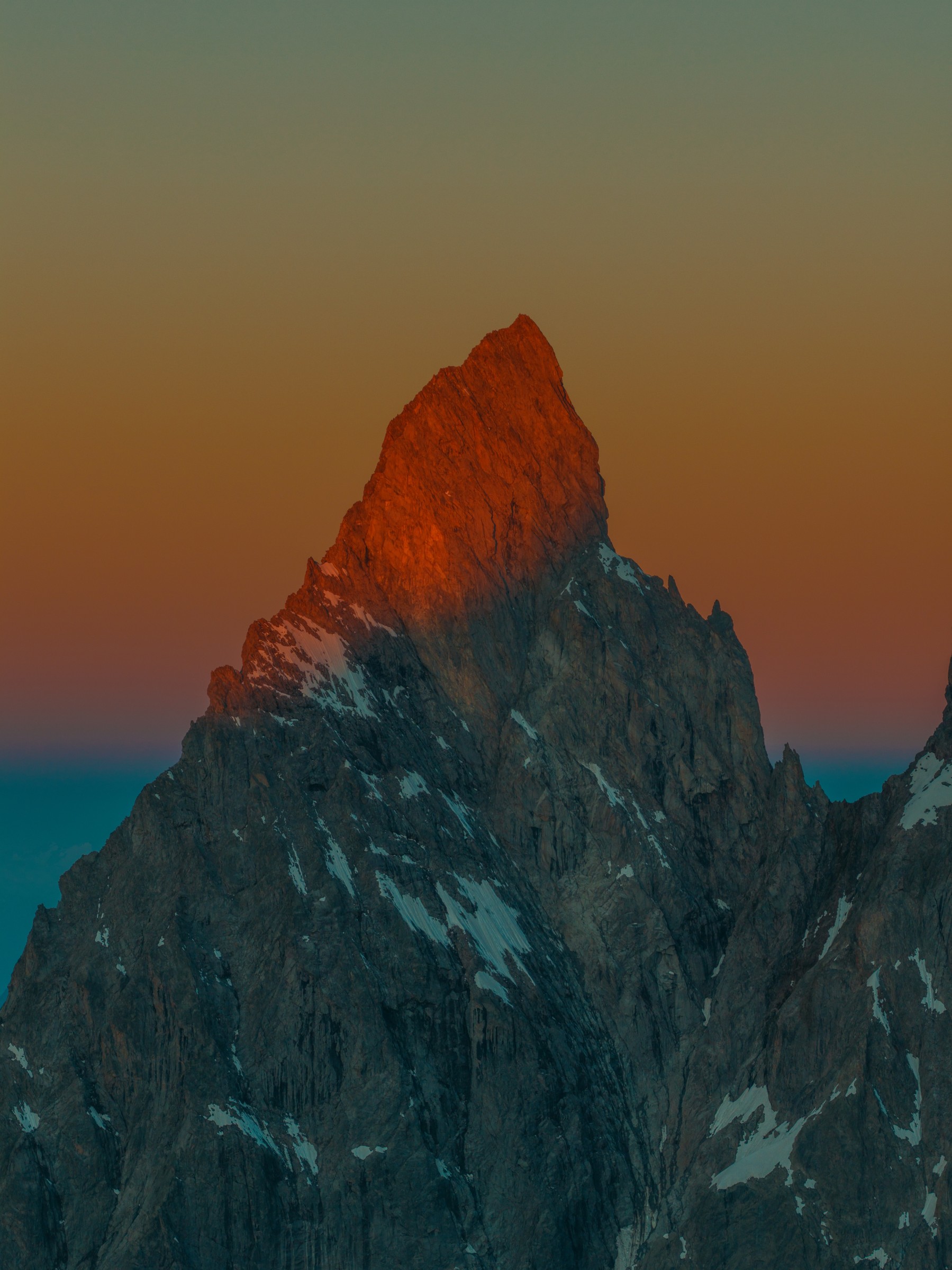 The upper Aiguille Noire de Peuterey lit red above shadowed rock faces