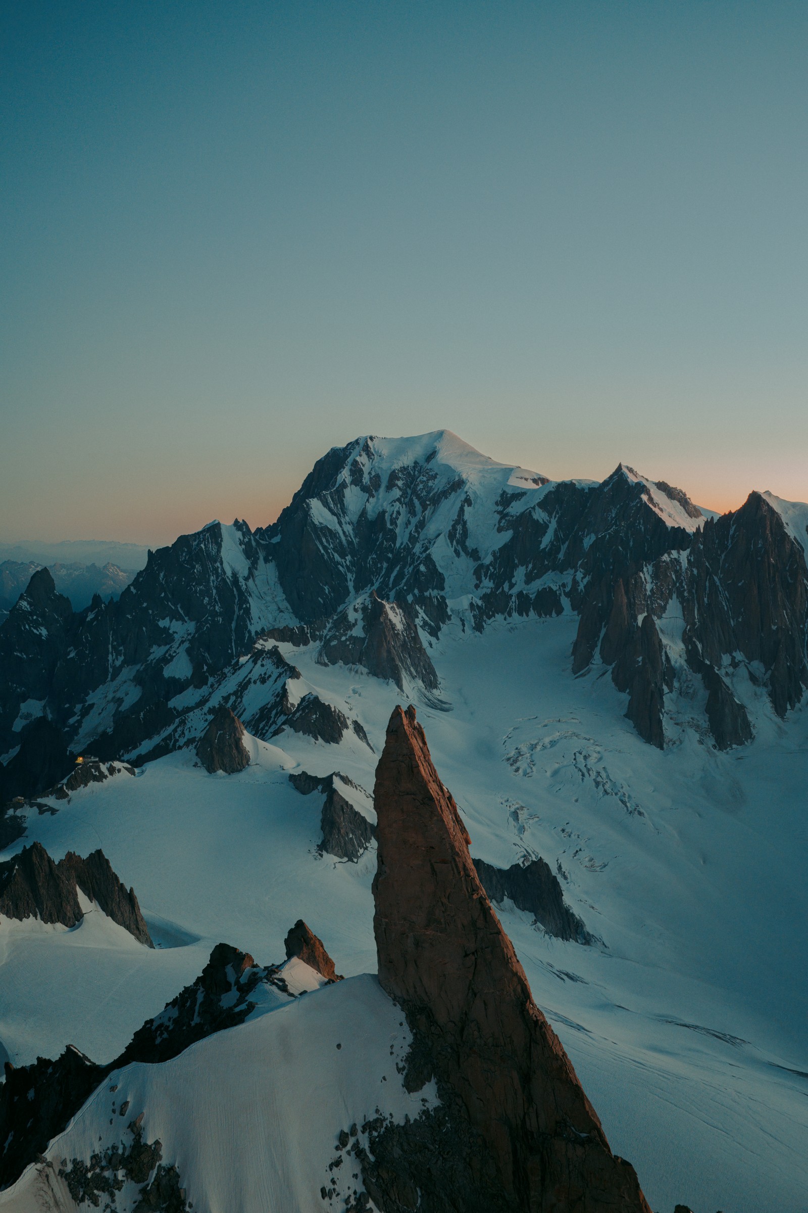A rock spire in the foreground, with glaciers and the Mont Blanc massif beyond